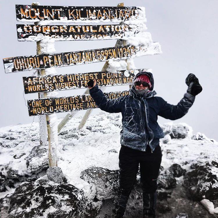 A client with high gaiters summits on a cold, snowy day